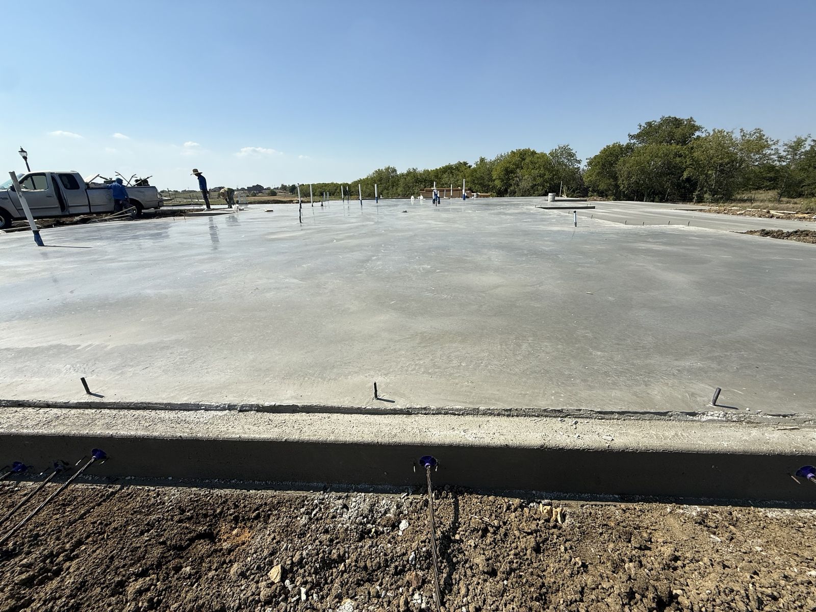 Freshly poured post-tension slab with cable tails extending from the slab edge