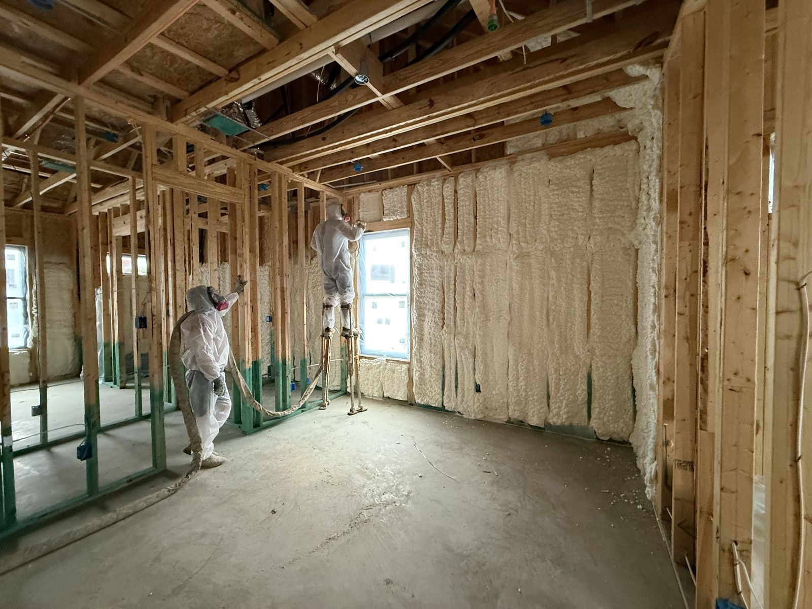Spray foam insulation being installed in a framed bedroom