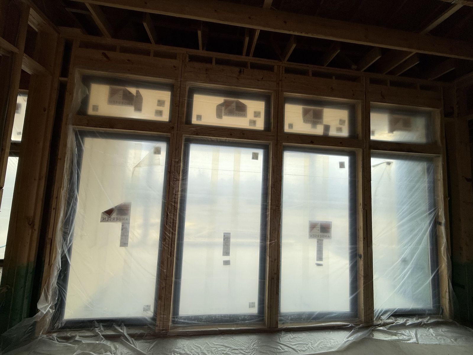 Framed wall of Andersen windows with transoms during construction